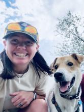Teacher smiling with white and brown dog.